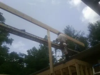 Carpenter setting a ridge beam over a new addition frame — Ice Dam Removal by Roofing Brothers in Greene