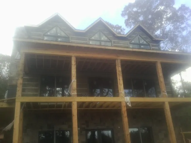 Dormers and porch framing on a large log home under construction — Roof Coating work by our crew in Greene
